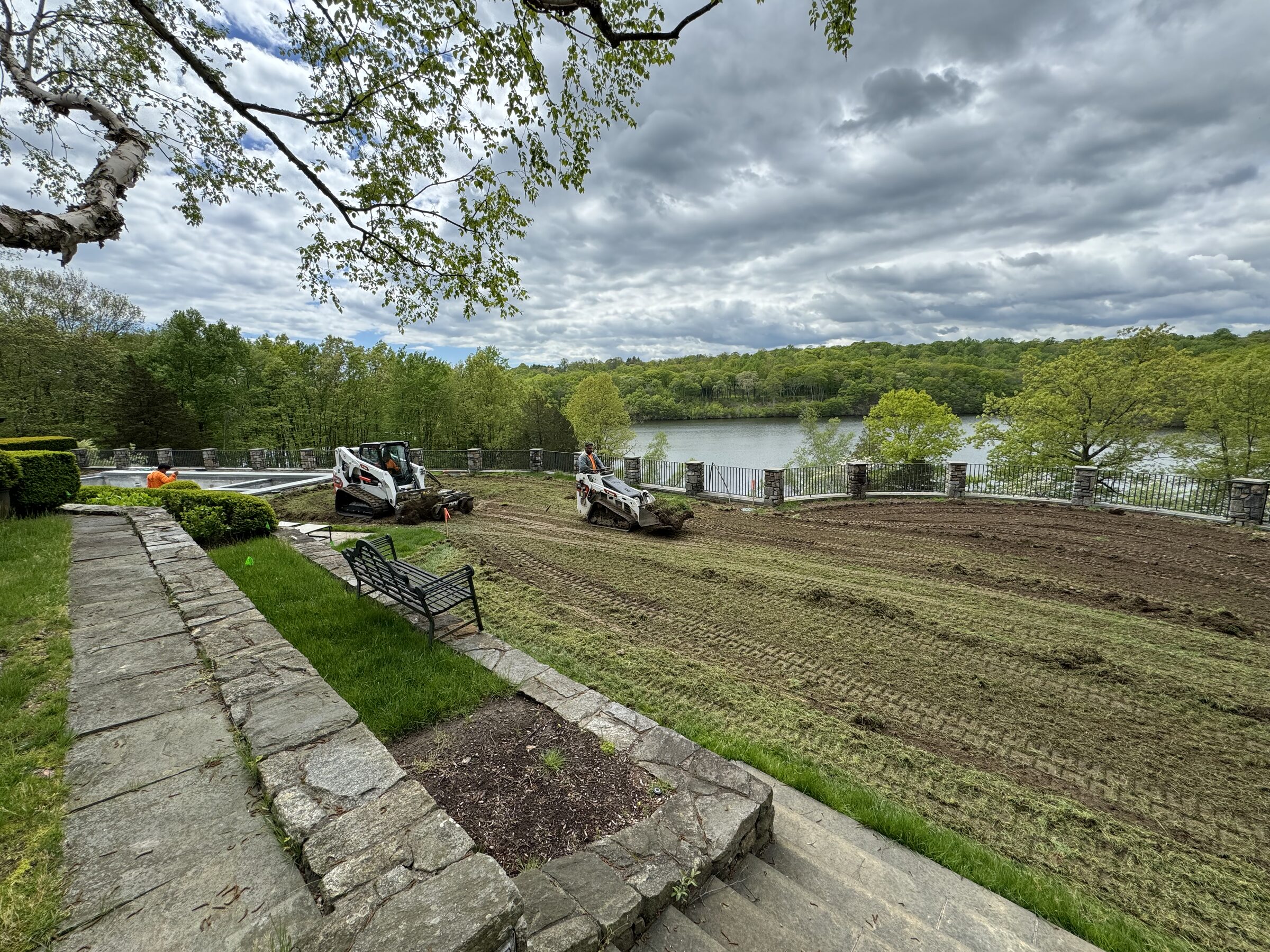 CT Sod crew running a Bobcat skidsteer to prep a large waterfront estate lawn install.