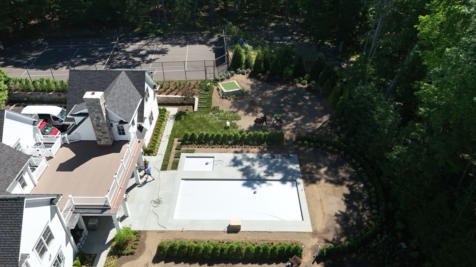Aerial view of the 17,000 square foot New Canaan estate mid-install — pallets of Kentucky bluegrass staged on the graded lawn as the crew lays rolls around the pool and putting green