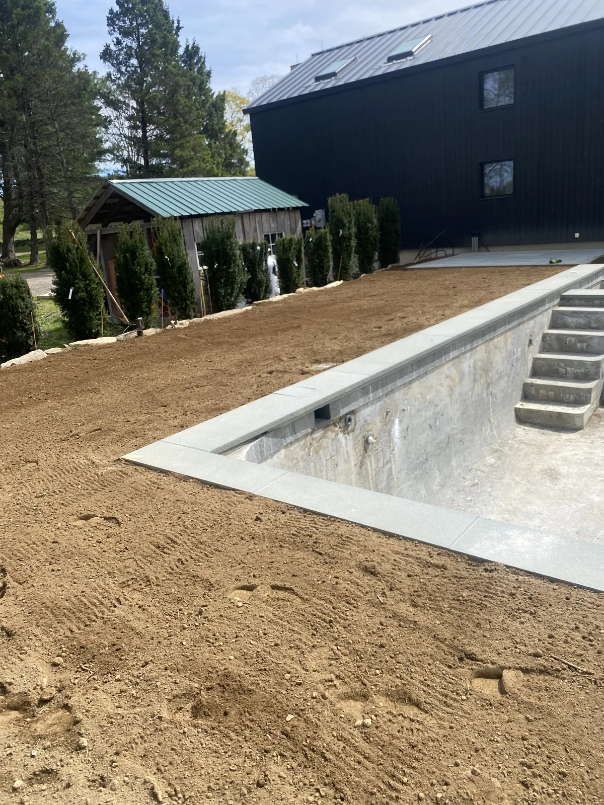 Warren CT sod install — prepped pool-surround lot with arborvitae plantings ready for fresh sod on a Lake Waramaug-area estate