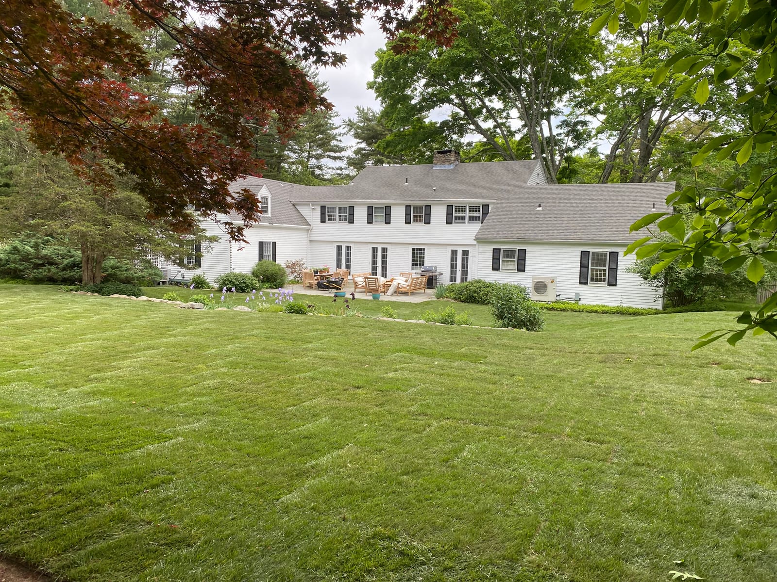 Finished 6,000 sq ft fresh sod lawn behind a white colonial home in Westbrook CT, green and complete after a one-day installation