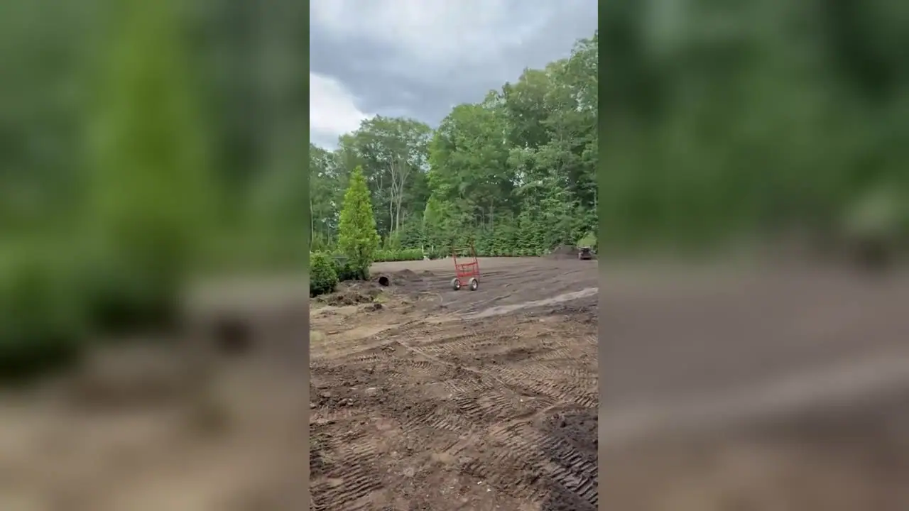 Stand-on track loader grading and leveling the back lawn of a New Canaan, CT estate during sod prep