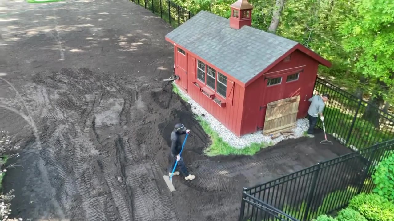 Drone fly-over of crew hand-grading and raking fresh topsoil to a finished grade around the outbuilding of a New Canaan, CT estate before sod is laid