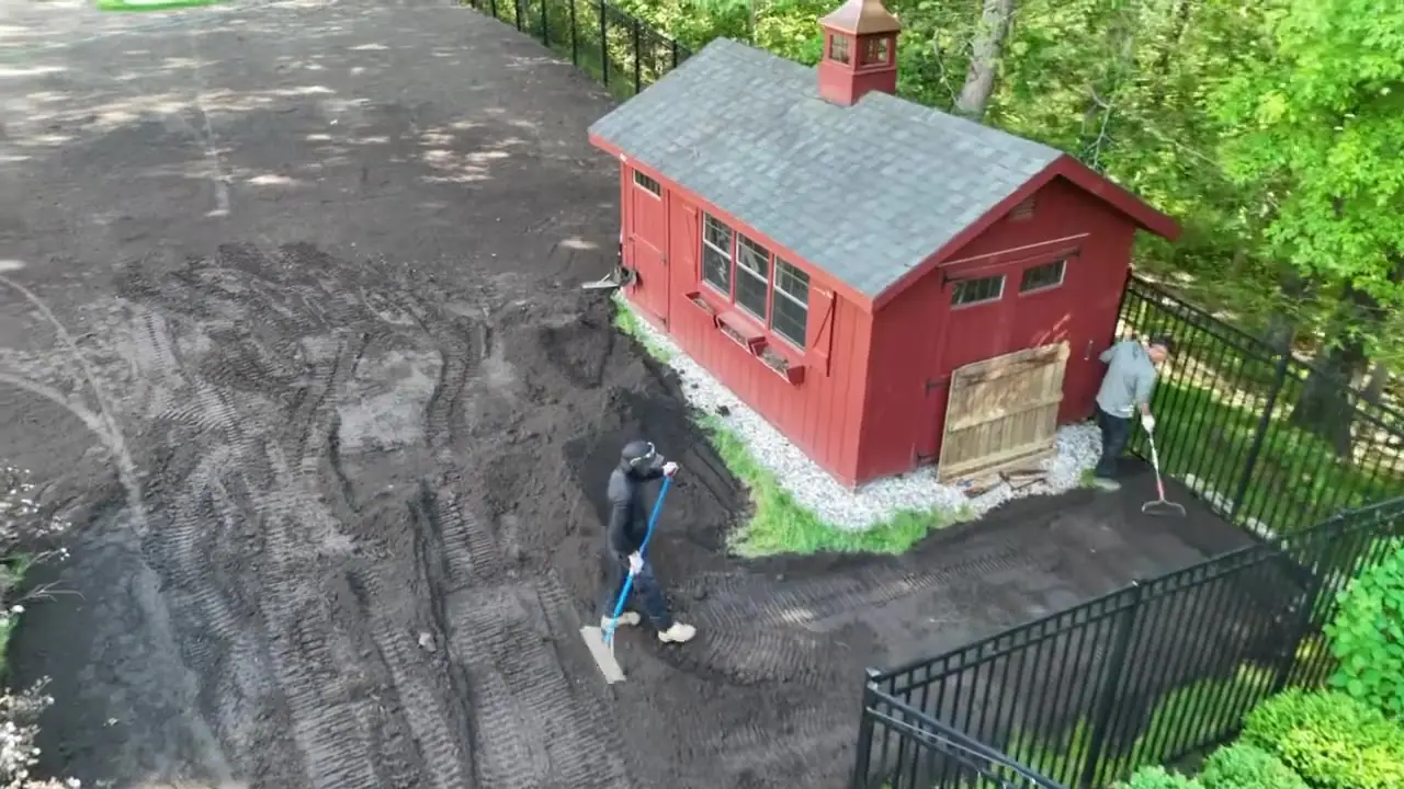 Drone fly-over of crew hand-grading and raking fresh topsoil to a finished grade around the outbuilding of a New Canaan, CT estate